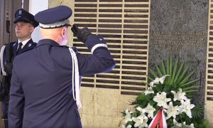 Policjant salutujący przy tablicy poległych policjantów