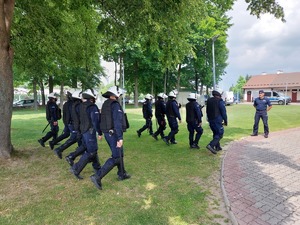 Policjanci którzy są ubrani w umundurowanie ćwiczebne stoją w dwuszeregu wykonując komendy wydawane przez dowódcę drużyny.
