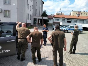 Funkcjonariusze Straży Leśnej oraz policjant stoją na placu Komendy Powiatowej Policji w Ropczycach