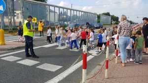 policjant z dziećmi na przejściu dla pieszych
